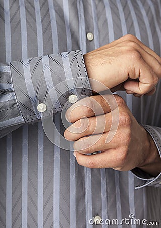 Close up detail of man`s hands buttoning shirt cuffs. Businessman getting ready for work. Men`s clothing apparel. Stock Photo