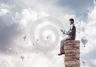 Man businessman on stack reading book and aerostats flying around Stock Photo