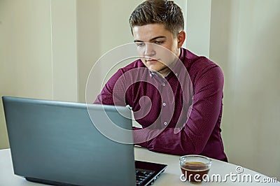 A man businessman working behind a laptop and drinking coffee. Work in the office. Business. Freelancer. Work at home Stock Photo