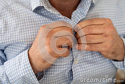 Man buttoning blue and white checkered shirt with his hands Stock Photo