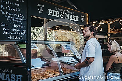 Man buying fresh pies from Pieminster market stand in Borough Market, London, UK. Editorial Stock Photo