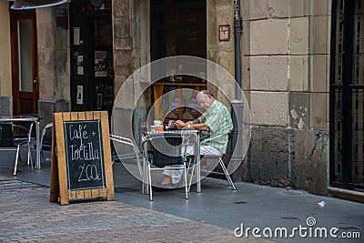 A man at a cafe table is reading a newspaper. Editorial Stock Photo