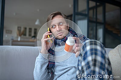 Blue-eyed man calling wife while asking her about pills Stock Photo