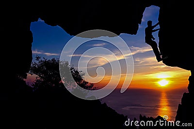 Man with camera climbing rock in the cave. Stock Photo