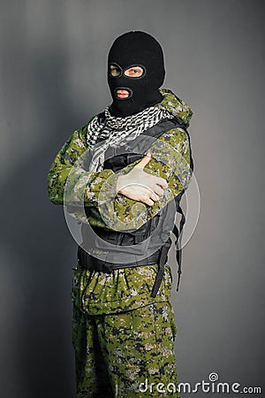 A man in camouflage and bullet proof vest, with a balaclava on his head. A special unit soldier, a modern warrior. Stock Photo