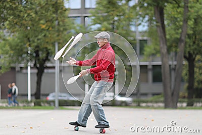 A man in a cap juggles with clubs Stock Photo