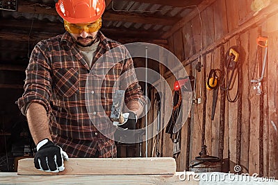 A man carpenter hammer a nail into a tree, male hands with a hammer close-up. Woodwork Stock Photo