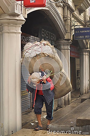 Man carrying big sack on street, morning view of Darjeeling, India as of April 12, 2012 Editorial Stock Photo