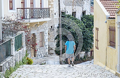 Man Carrying A Boy On His Shoulders Walking Down Steps on Symi, Greece Editorial Stock Photo