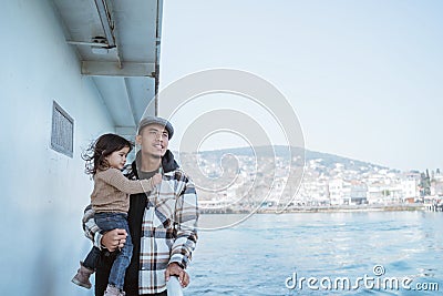 man carrying his daughter leaning against the railing of the ferryboat Stock Photo