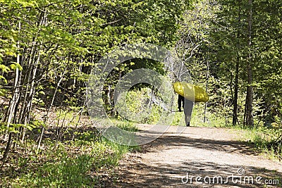 Man carrying a white water kayak and paddle up an outdoor trail Stock Photo