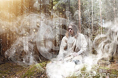 A man in a cassock spends a ritual in a dark forest Stock Photo