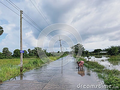 A man is catching fishes on flooded road in Thailand Editorial Stock Photo