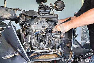 A man of Caucasian descent is fixing his malfunctioning motorbike. Stock Photo