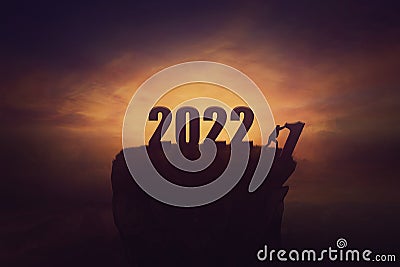 Man changing the new year numbers, replacing 2021 with 2022, throwing the old digit off the peak. Surreal and conceptual scene, Stock Photo