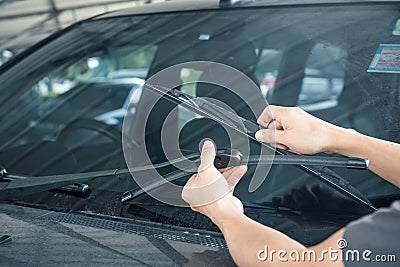 Man is changing windscreen wipers on a car Stock Photo