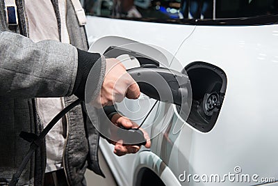 Man charging electro car. Man holding in hand power cable supply ready to plugged in into charging port Stock Photo