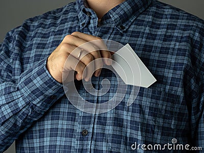 A man in a checked blue shirt tucks a business card into his pocket Stock Photo