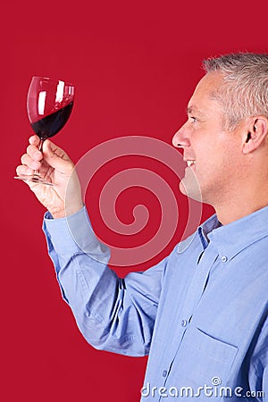 Man checking a glass of red wine for clarity Stock Photo