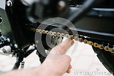 Man checks the chain tension in motorcycle Stock Photo
