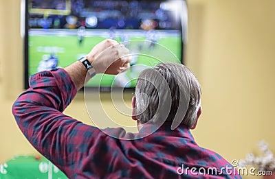 Man cheers for team while watching football game on TV Stock Photo