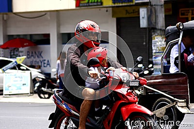 A man and a child riding in tandem on a motorcycle in Antipolo City. Editorial Stock Photo