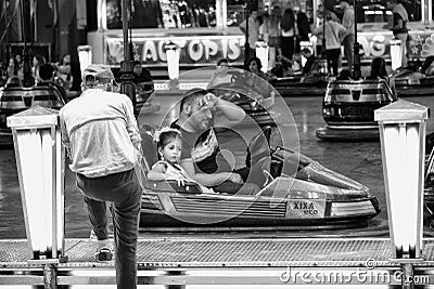 Man and child take a break from driving a dodgem car at the fair. Velez Malaga, Spain. Editorial Stock Photo