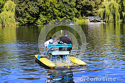 A man with 2 children, Hasidic Jews, ride a catamaran on a lake in the autumn Sofia park in Uman, Ukraine Editorial Stock Photo