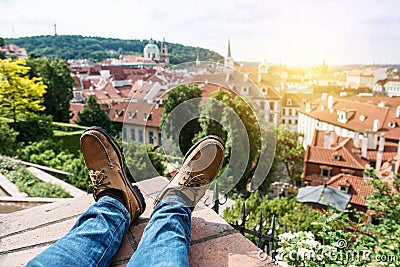 Man chilling on the rooftop sitting on the edge wearing leather shoes and enjoy the view of old town Prague, Czech Republic. Stock Photo