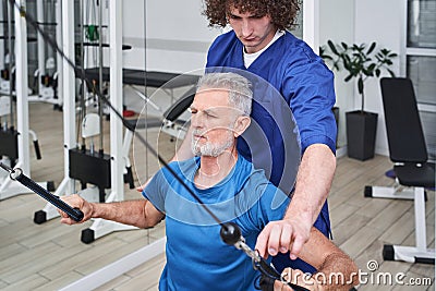 Man chiropractor or osteopath correcting old man patients movements during rehabilitation Stock Photo