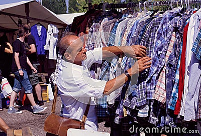 Man choosing shirt on sale of outdoor flea market Editorial Stock Photo