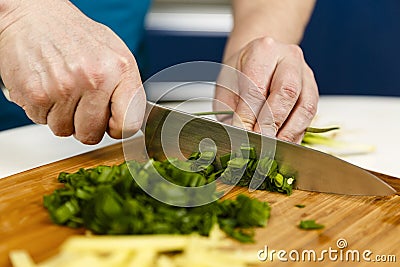 Man chopping spring onions on a wooden board Stock Photo