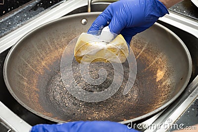 man cleaning a dirty cooking pan at horizontal composition Stock Photo