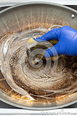 man cleaning a dirty cooking pan vertical composition Stock Photo