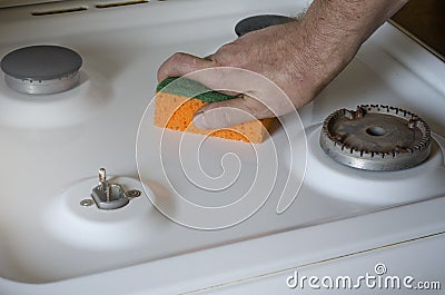 Man is cleaning the stove with kitchen sponge Stock Photo