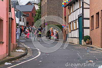 Man cleaning up the littered street by sweeping the trash away with a broom while people are celebrating and dancing Editorial Stock Photo