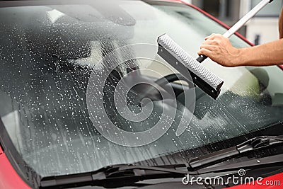 Man cleaning windshield with glass wiper, closeup Stock Photo