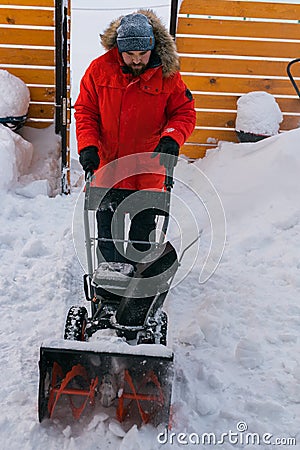 A man clear snow from backyard with snow blower. Winter season and snow blower equipment Stock Photo