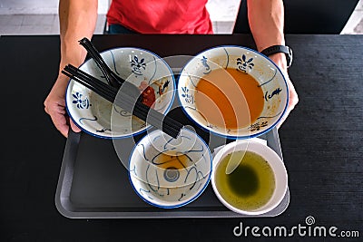 Man clearing tray of used crockery after dining. Diners at coffee shops, food courts are expected to clear their tables, dirty Stock Photo