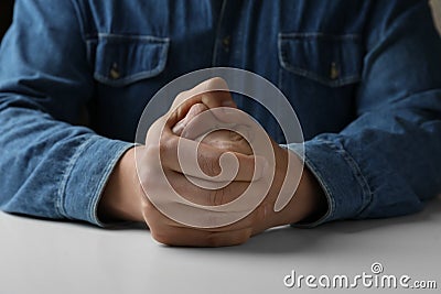 Man clenching hands at table while restraining anger, closeup Stock Photo