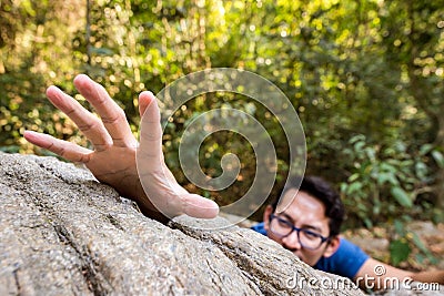 Man climb rock in the forest and hand for help Stock Photo