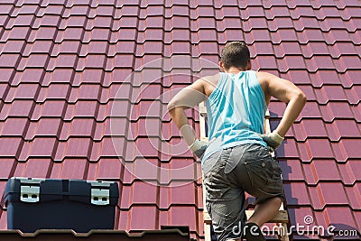 The man climbed onto the roof of the house with tools to repair it Stock Photo