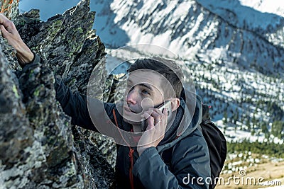 Man climbing the mountain to the top and talking on the phone. Communications and goal achievement in career Stock Photo