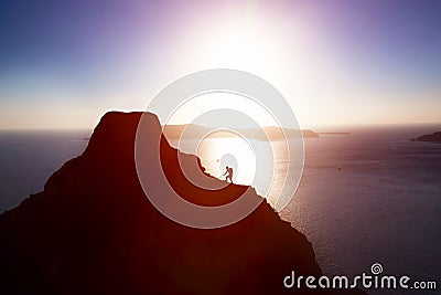 Man climbing up hill to reach the peak of the mountain over ocean. Stock Photo