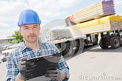 Man with clipboard forklift unloading lorry in background Stock Photo