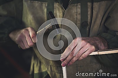 Man clogs a nail wooden frame for bees. Hands with long thin fingers hold wooden frame. Stock Photo