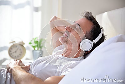 Man with closed eyes listening music lying in bed closeup Stock Photo