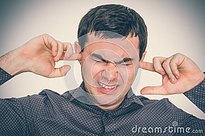 Man closes ears with fingers to protect from loud noise Stock Photo