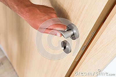 Man closing a light wood interior door Stock Photo