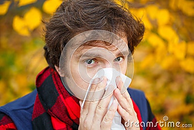 Man with cold rhinitis on autumn background. Fall flu season. Il Stock Photo